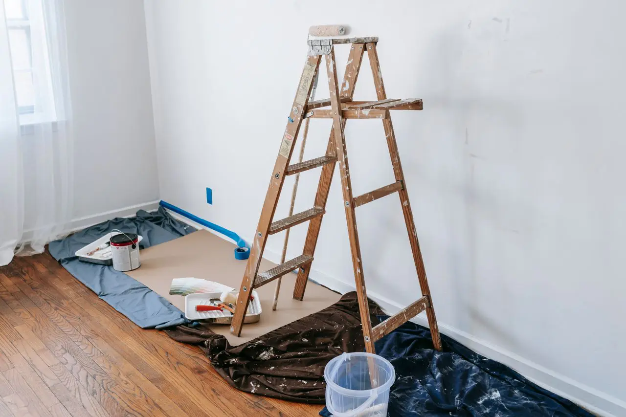Paint-spattered ladder, drop cloths, and color swatches set up for accent wall painting in a Lafayette LA home